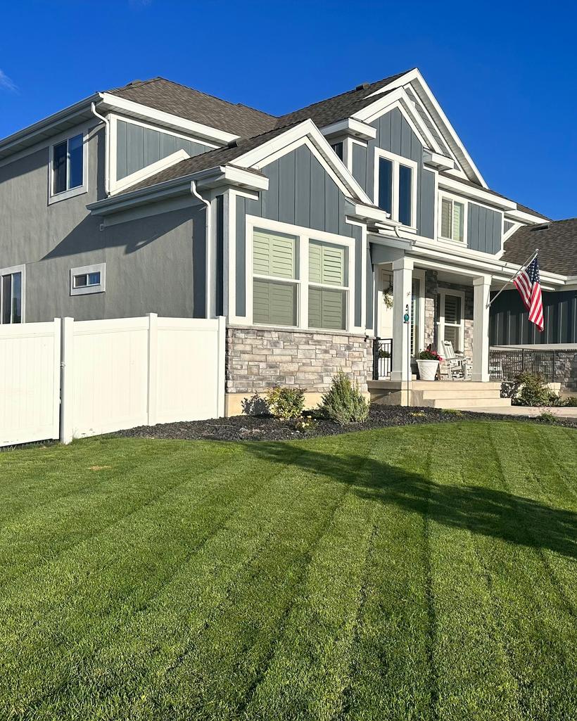 A two-story home with a freshly striped green lawn and clean planting beds along the walkway